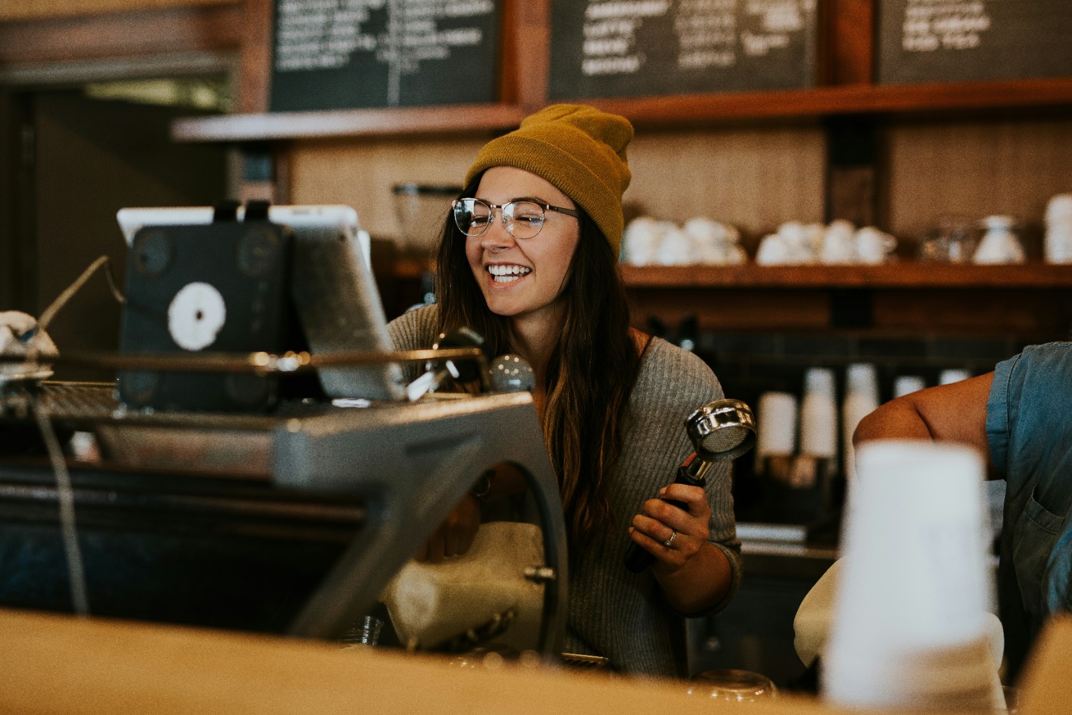Café worker serving customers behind an espresso machine